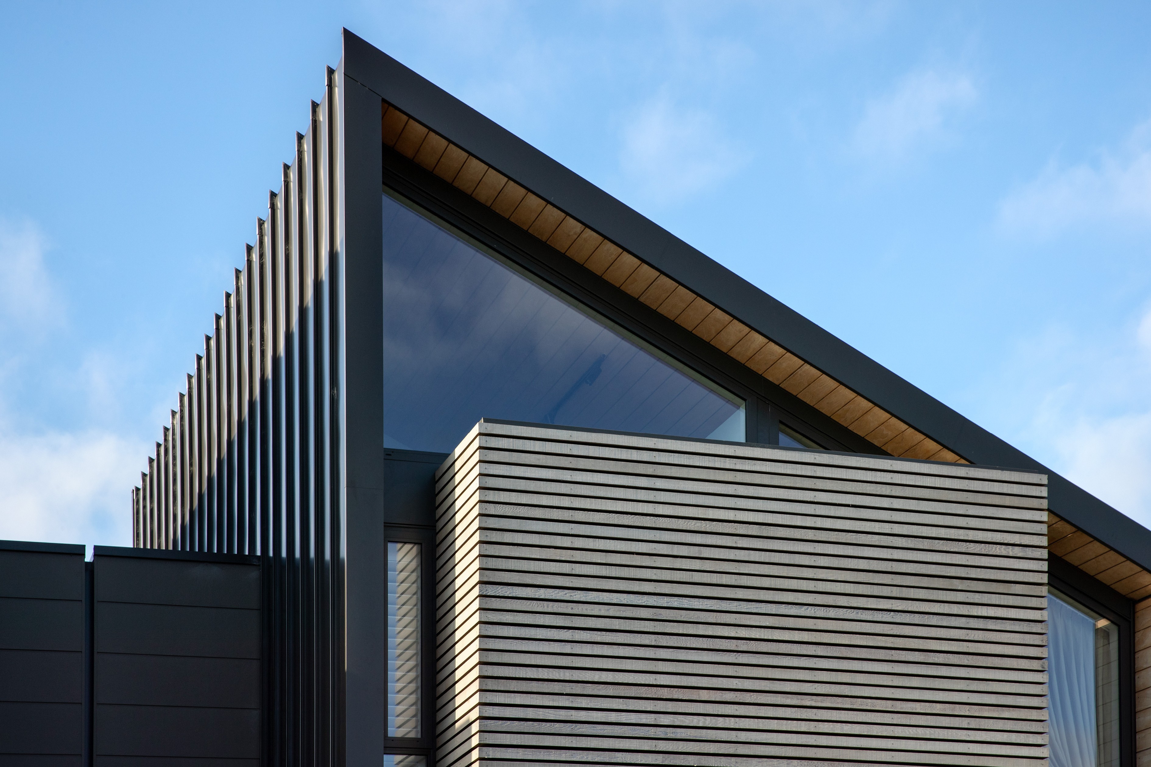 Angled steel roof of an inner-city apartment backed by blue sky